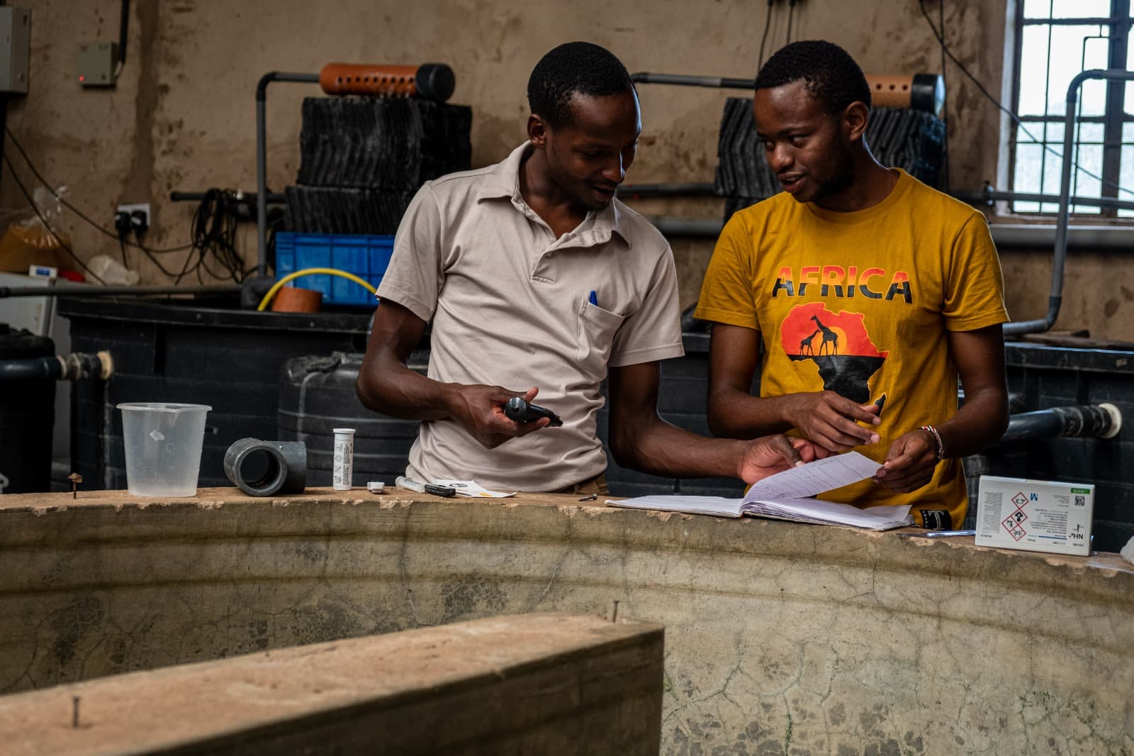 Two men in a workshop discussing some notes in a notepad
